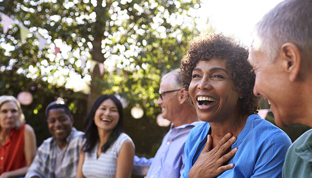 Group Of Mature Friends Socializing In Backyard Together